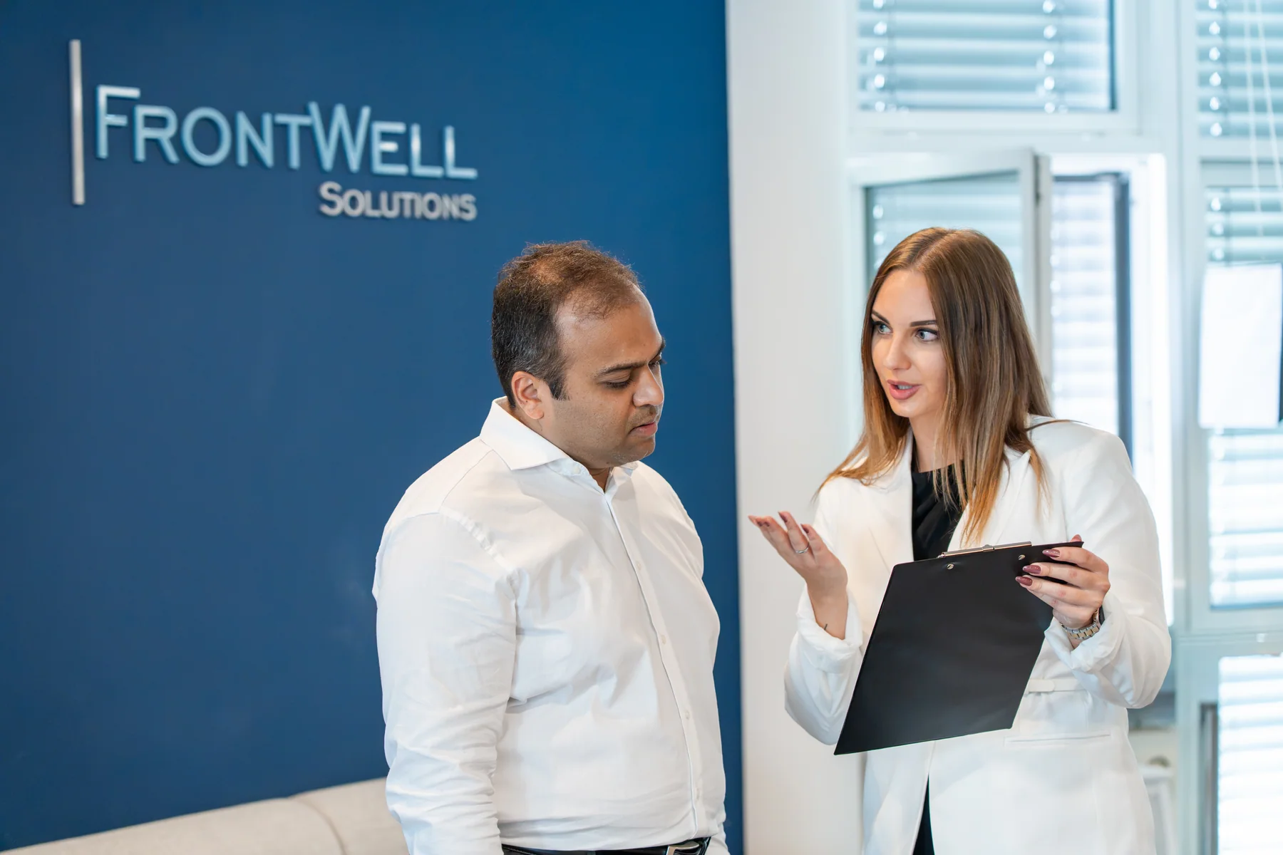 Two FrontWell colleagues discussing work in front of the FrontWell office wall.