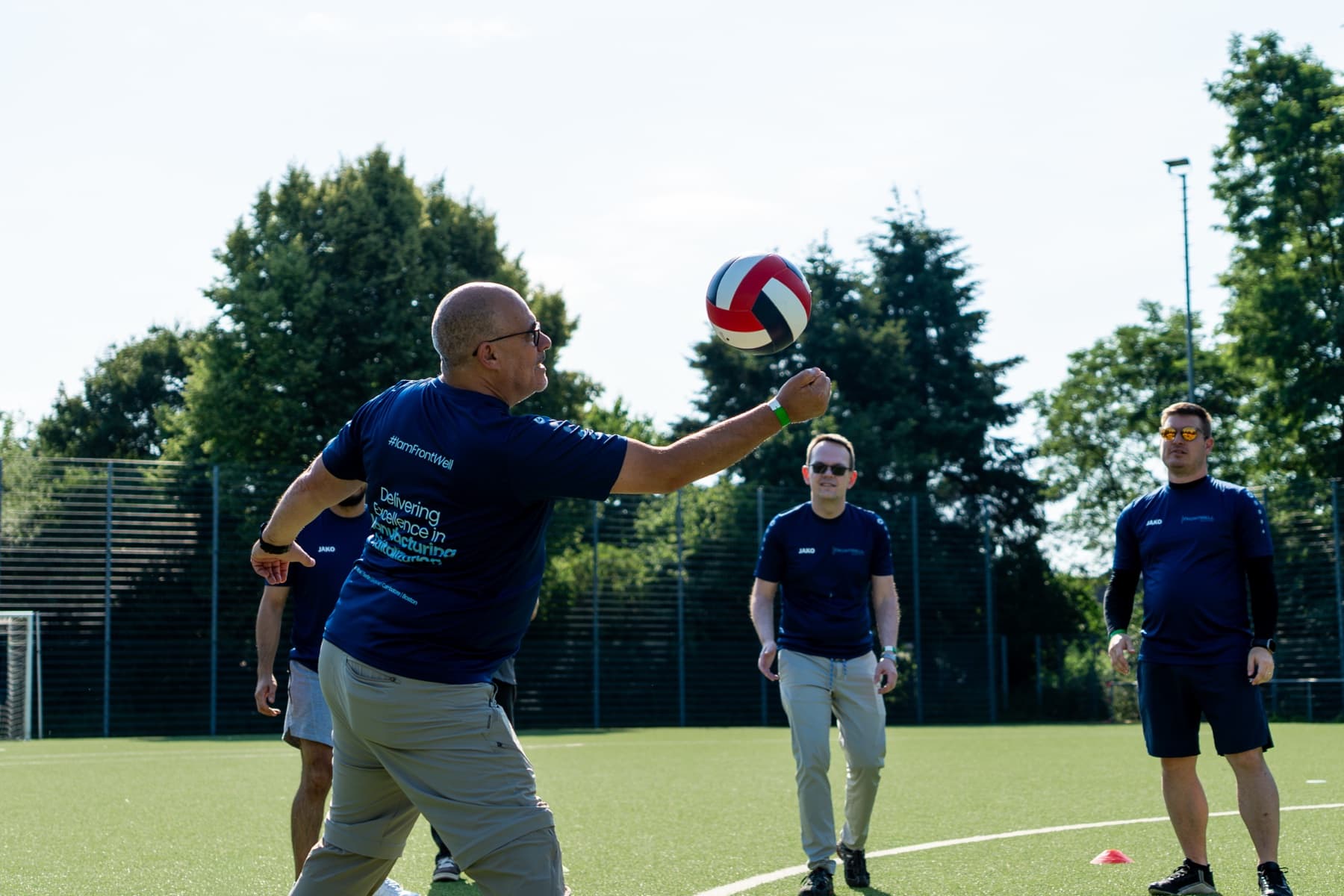 FrontWell colleagues playing volleyball together outdoors.