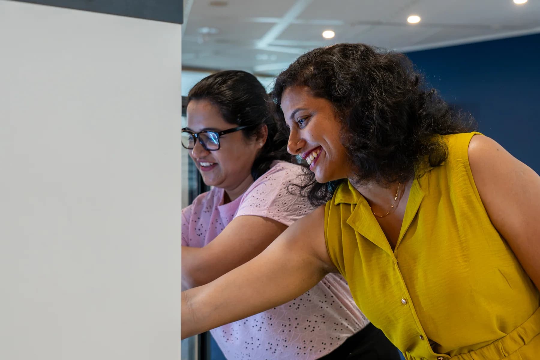 Two FrontWell colleagues smiling while working together at a screen.