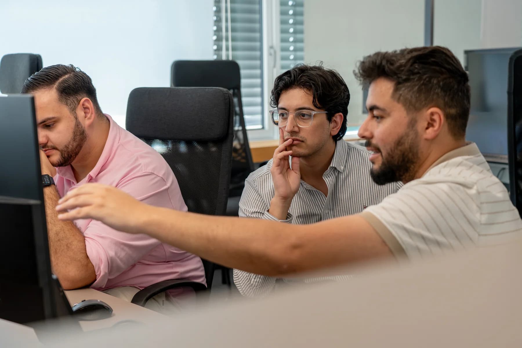 Three FrontWell colleagues working through a question together at a computer.